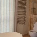 Baño con una bañera exenta de diseño curvo, acompañada de cortinas elegantes y revestimientos en cerámica