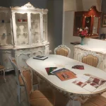 Conjunto clásico en tonos claros con mesa de acabado dorado, sillas refinadas, vitrina y aparador de estilo armonioso y accesible
