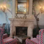 Rincón con chimenea, butaca y mesa de diseño, acompañado de candelabros y detalles decorativos de gran estilo